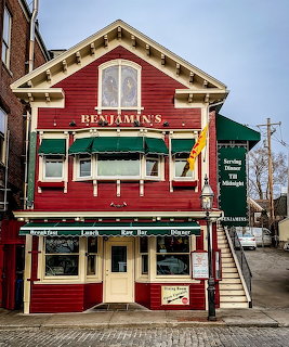 Red two-story wooden restaurant building with Benjamin's sign, green awnings, and dining signage