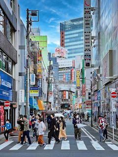 Crowded crosswalk in Akihabara district with tall buildings and bright commercial signage