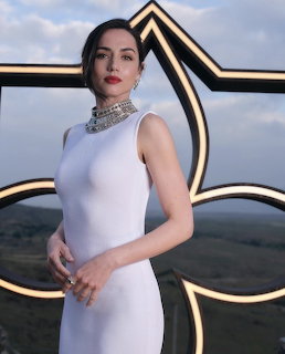 Woman in white sleveless dress with diamond choker necklace posing at outdoor event