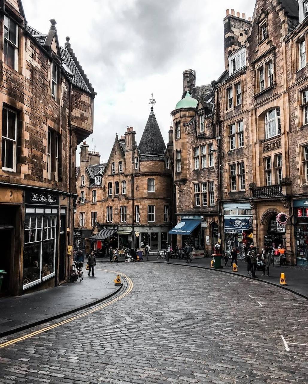 Cobblestone street in Edinburgh with historic stone buildings and people walking