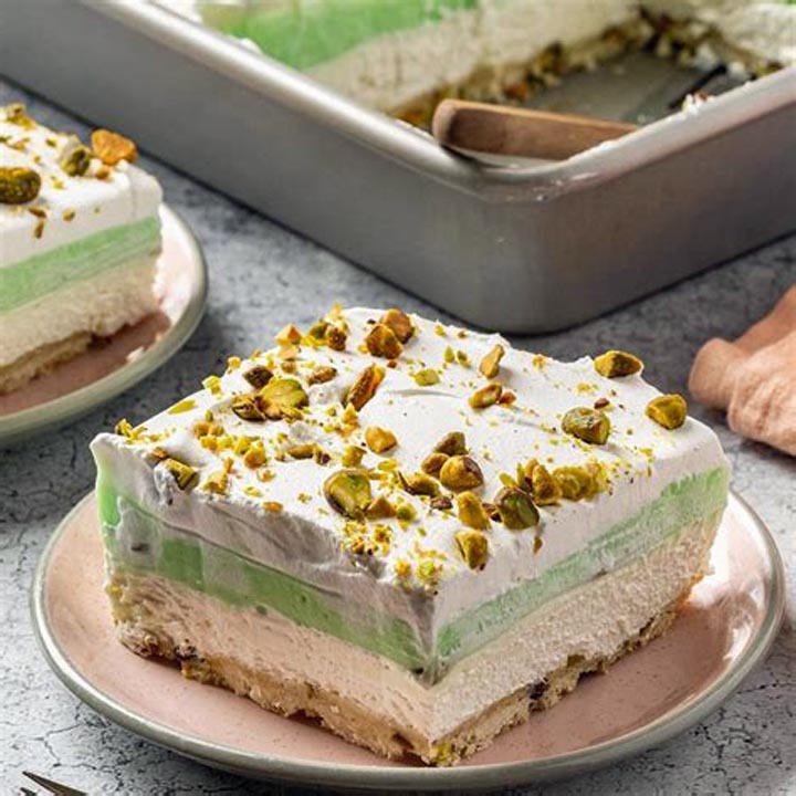 Slice of layered pistachio pudding dessert with whipped cream and crushed pistachios on top