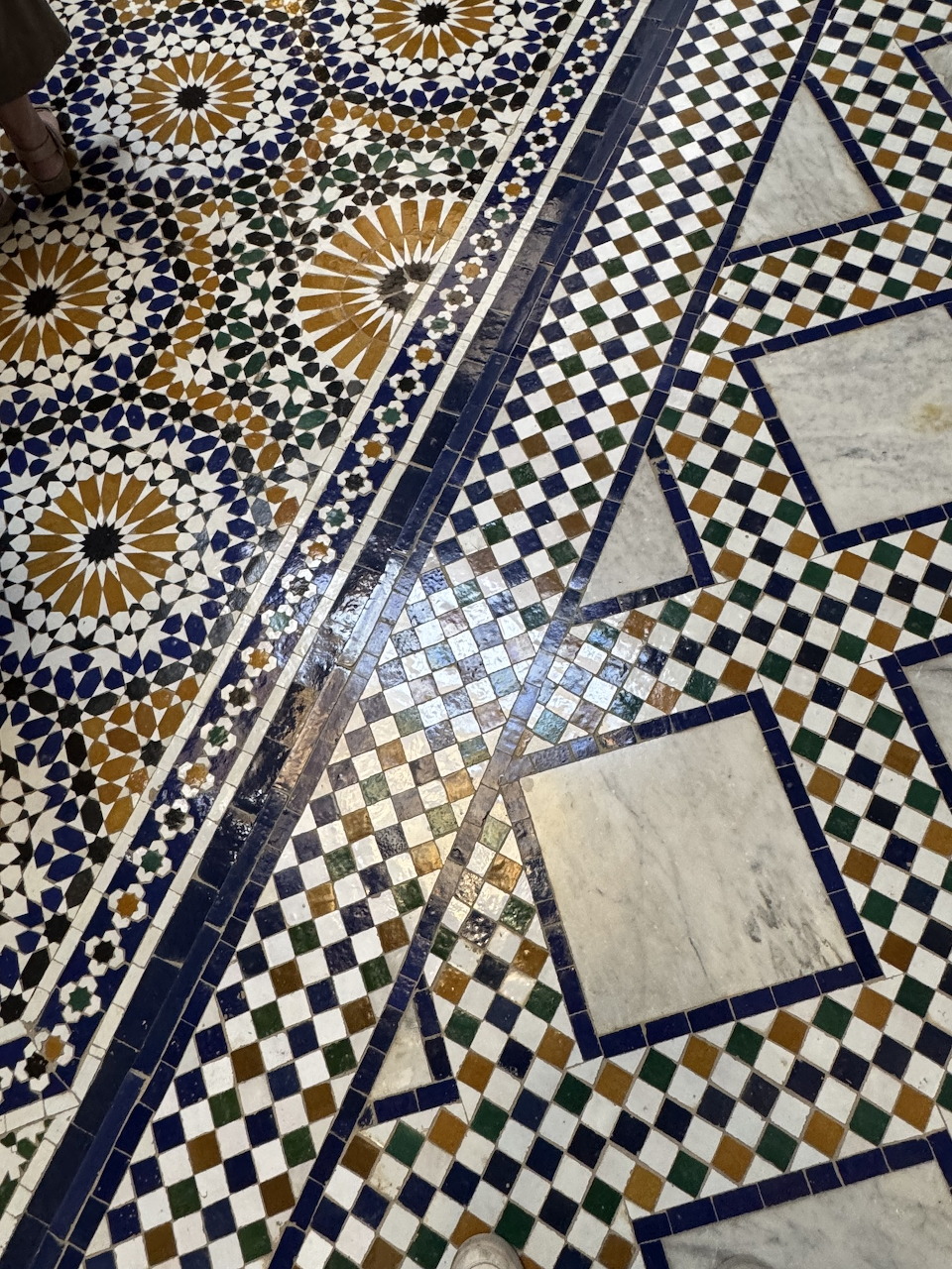 Ornate Moroccan mosaic floor with geometric star patterns and checkered tiles in blue, gold, and cream