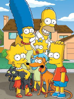 The Simpsons family posing together outside their Springfield home with blue sky and clouds in the background
