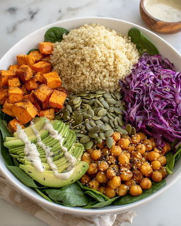 Colorful buddha bowl with quinoa, sweet potato, avocado, chickpeas, purple cabbage, pumpkin seeds, and spinach