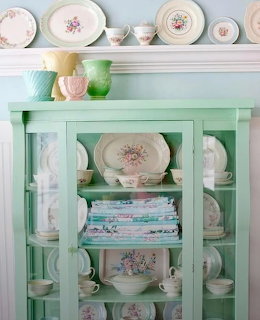 Mint green vintage cupboard with pastel floral china and white ceramic figurines on display shelves