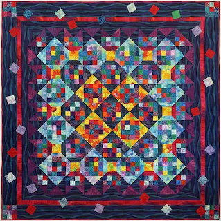 Colorful geometric patchwork quilt with diamond patterns and red border on dark blue fabric