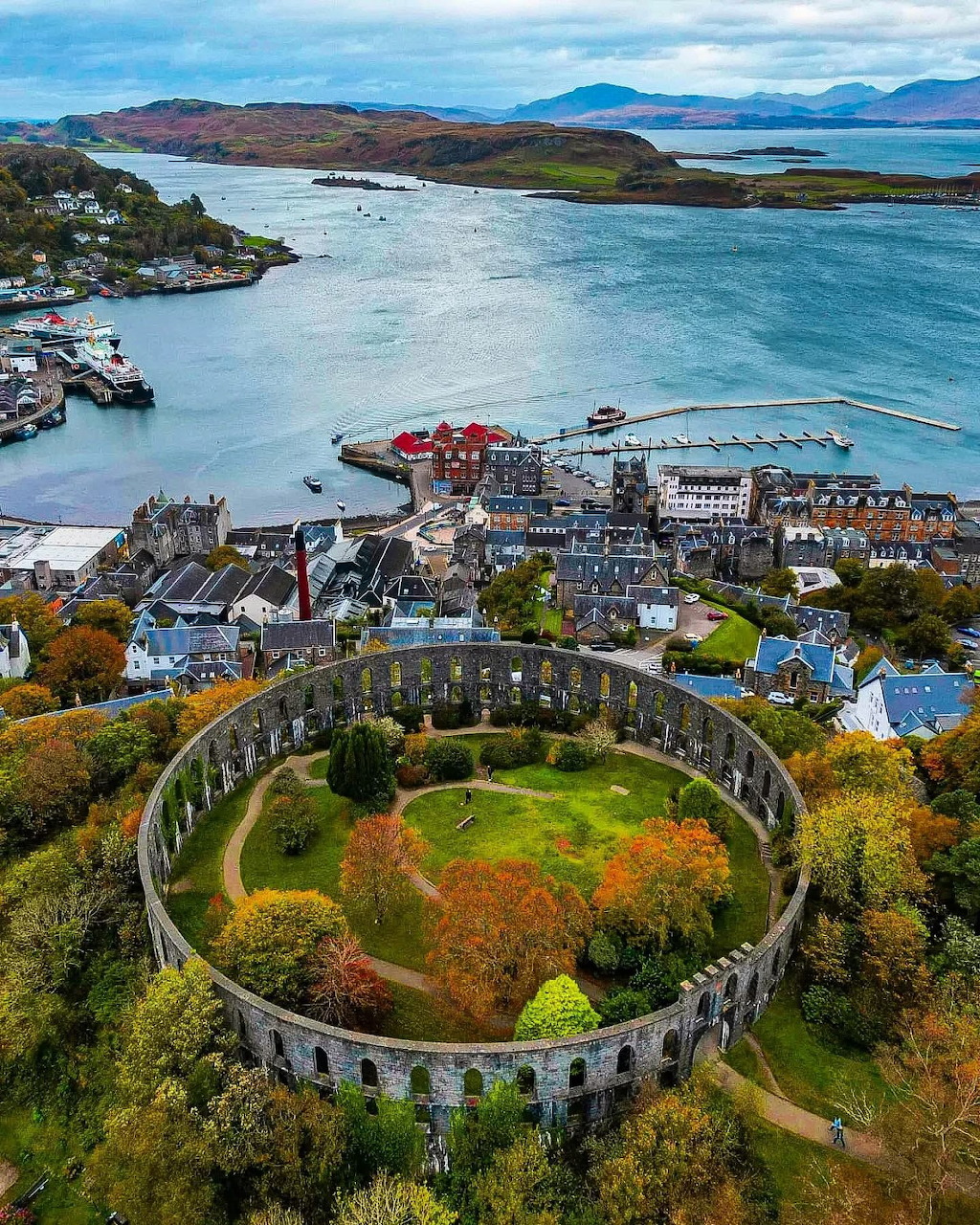 Aerial view of Oban Scotland with McCaig's Tower circular monument, harbour, and coastal islands