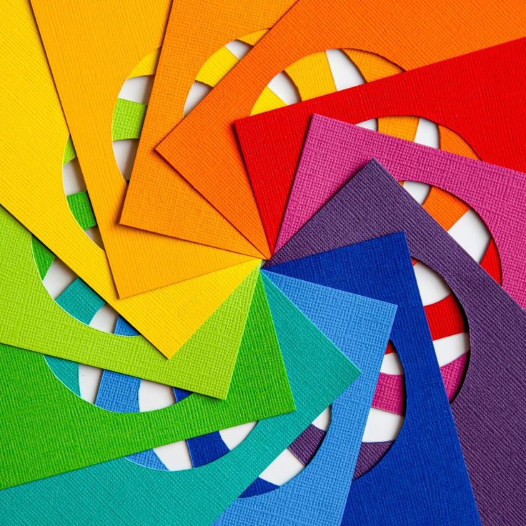 Rainbow-colored textured paper wedges arranged in a spiral over a striped circle