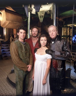 Four people in historical costumes posing on an elaborate vintage submarine set with brass details