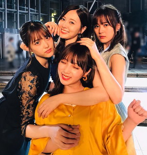 Four young women hugging and posing together indoors