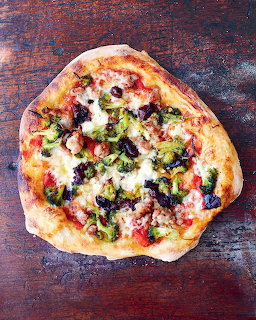 Overhead view of a round pizza with colorful vegetable toppings on wood surface
