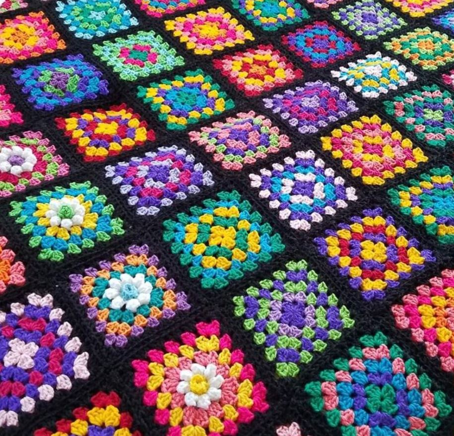 Colorful crochet granny squares blanket with black borders arranged in a grid pattern