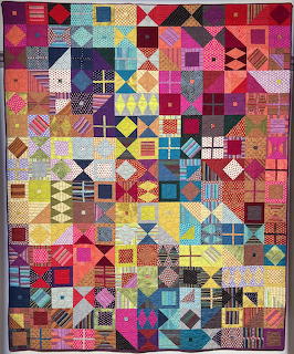 Colorful patchwork quilt with geometric patterns in squares arranged in a dense grid