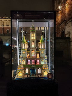 Illuminated miniature church model in a glass display case at a Christmas exhibition in Krakow at night