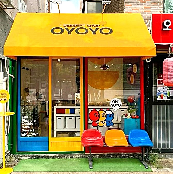 Bright yellow and blue dessert shop exterior with colorful seating and large windows