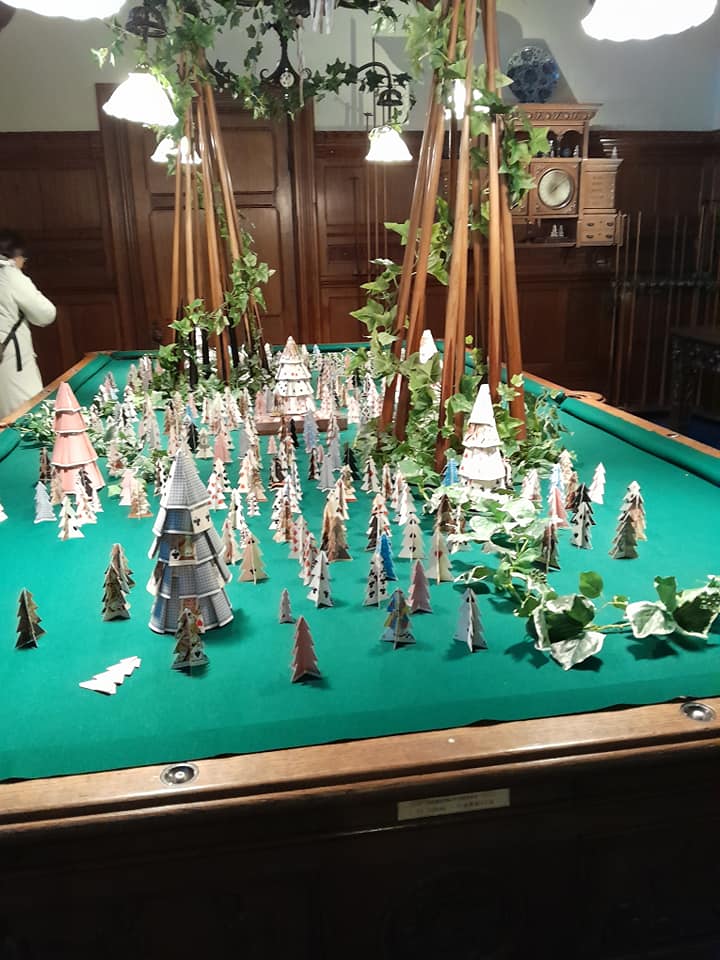 Miniature Victorian Christmas tree display arranged on a green billiard table in a historic interior room