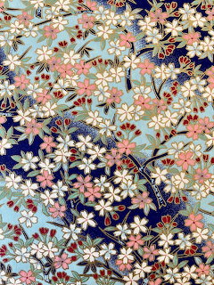 Ornate Japanese kimono fabric with colorful floral patterns, cherry blossoms, fans, and gold detailing on navy blue