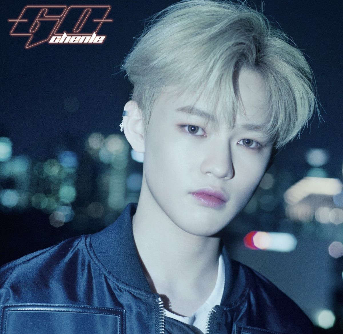 Close-up portrait of Chenle with blond hair and a blurred night city background