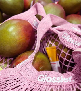 Fresh mangoes inside a pink mesh net bag with a small yellow tube product