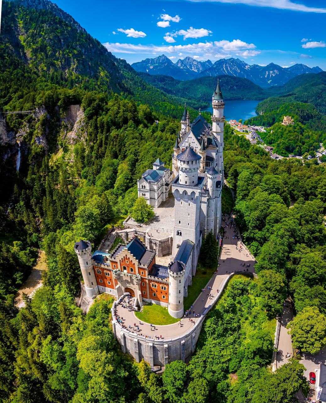 Aerial view of Neuschwanstein Castle surrounded by green forests and mountains in Bavaria, Germany