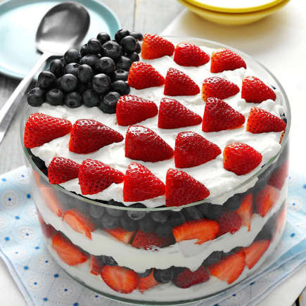 Patriotic trifle with strawberries and blueberries arranged as American flag on whipped cream layers