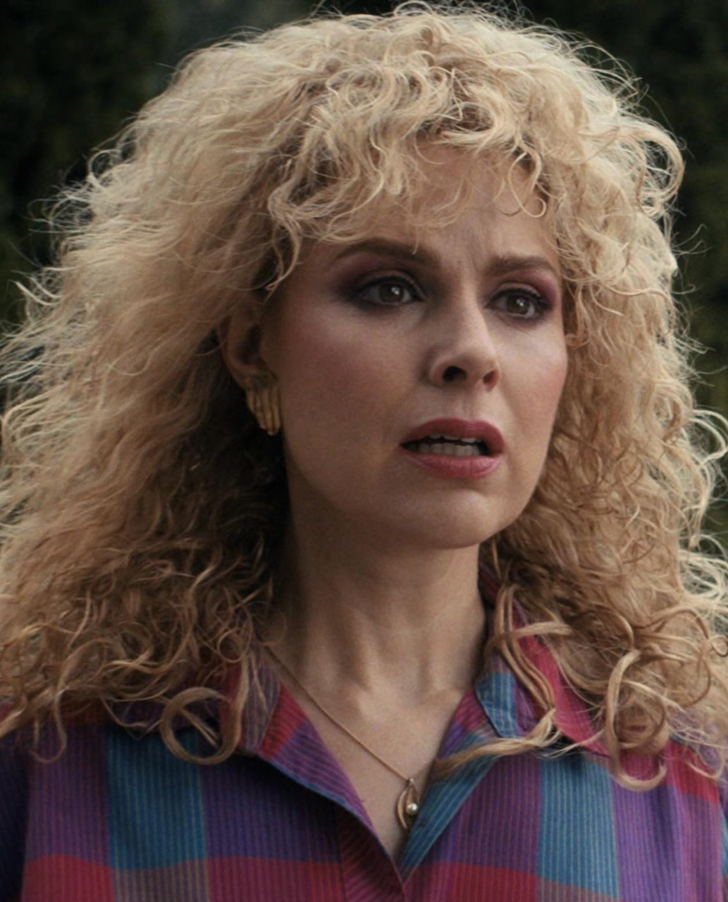 Woman with curly blonde hair and colorful plaid shirt in a retro 1980s style scene