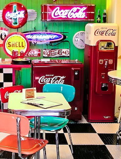 Retro 1950s diner interior with colorful chrome furniture, neon signs, and vintage vending machines