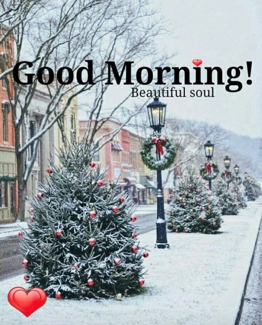 Snow-covered street with decorated Christmas trees, lamp posts, and colorful town buildings in background