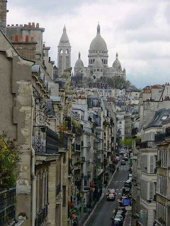 Montmartre street in Paris leading toward the Sacré-Cœur Basilica on a cloudy day