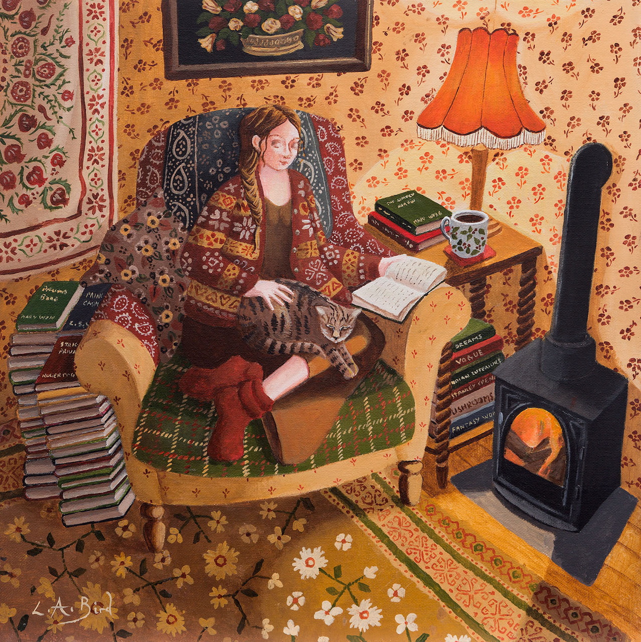 Woman in armchair with cat reading book by orange lamp and wood stove in patterned cozy room