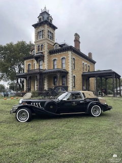 Black vintage car on a lawn in front of a historic mansion