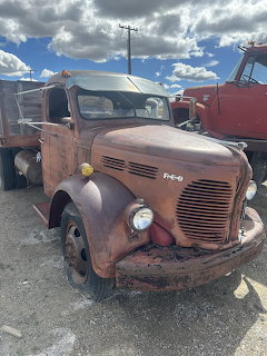Rusty vintage truck parked in a scrapyard under a cloudy sky
