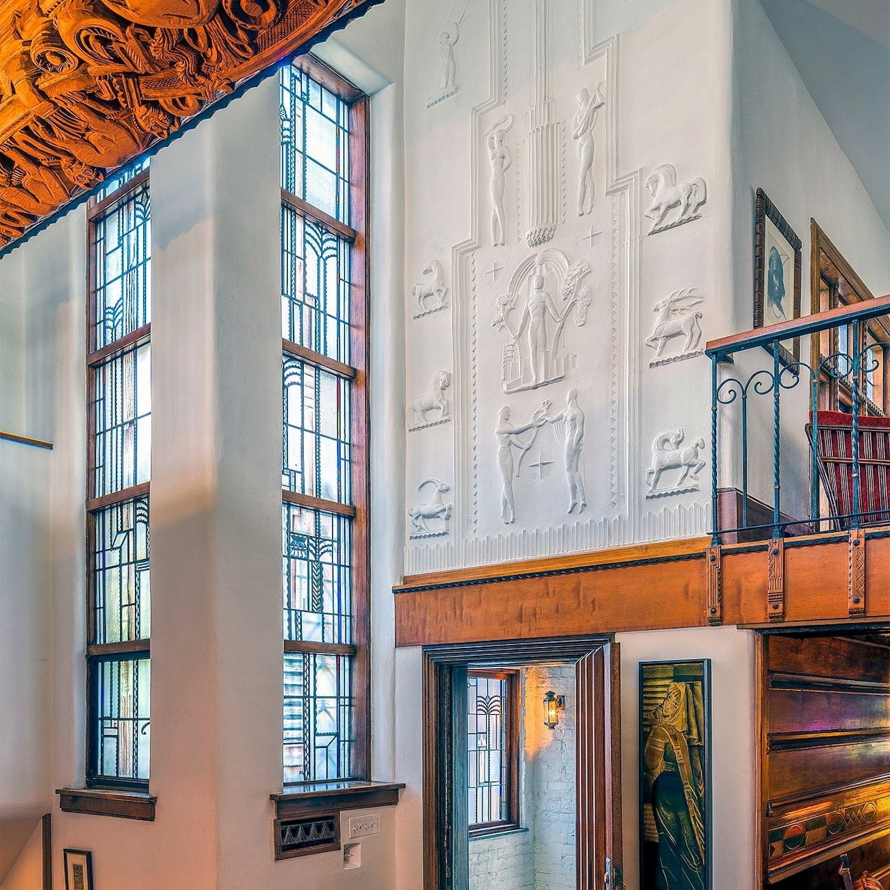 Art deco interior with stained glass windows, relief sculptures, ornate ceiling, and metal balcony
