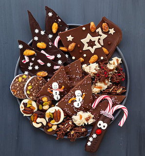 Round chocolate cake with Christmas candy canes, gingerbread men, chocolate shards, and white star decorations
