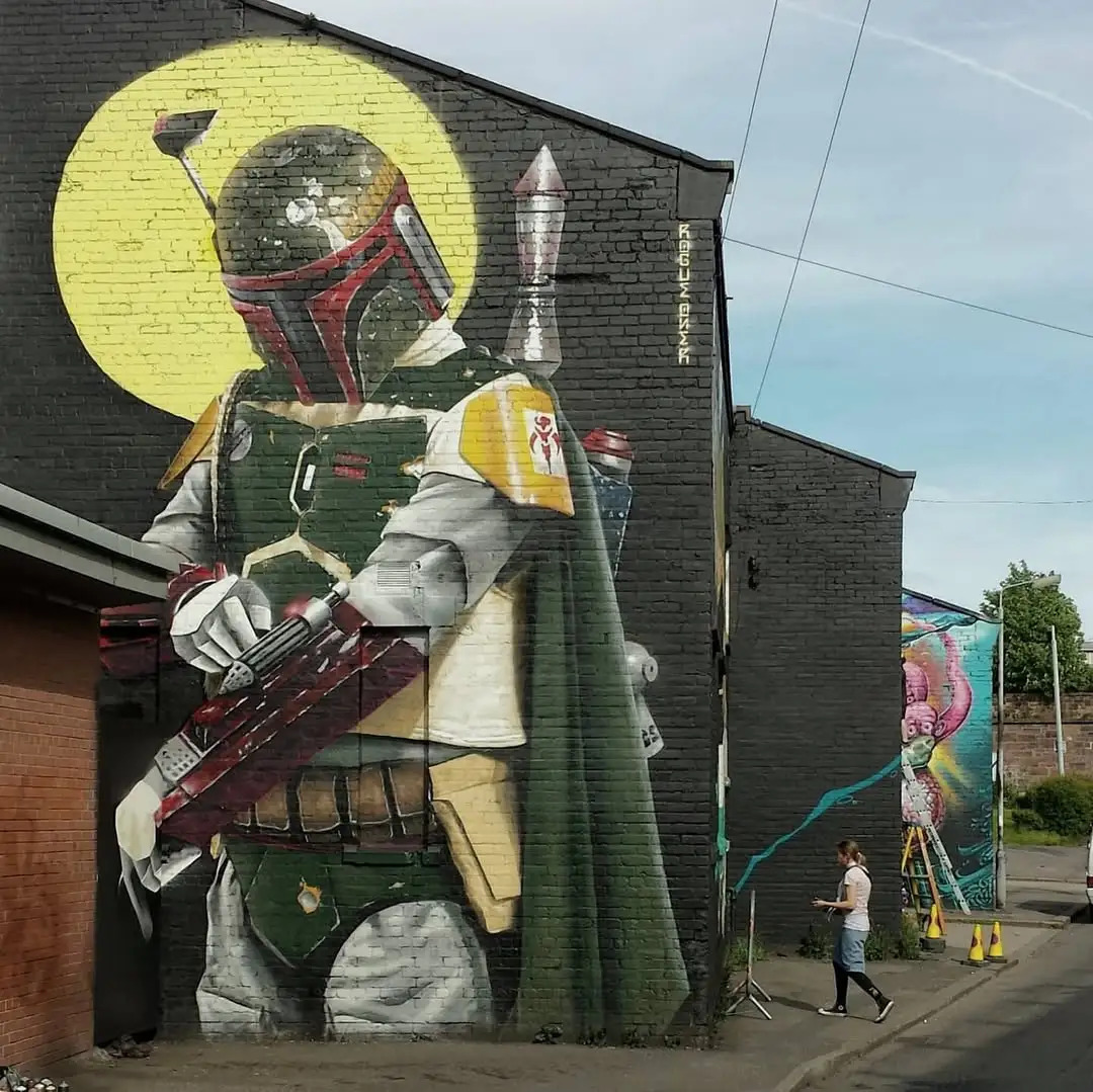 Large Boba Fett mural on building exterior with person walking past for scale