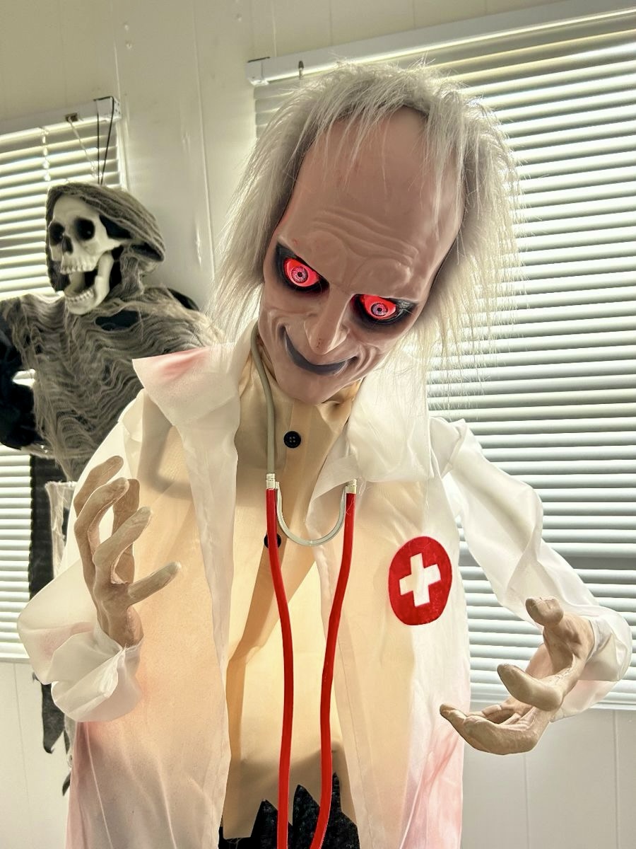 Halloween surgeon prop with glowing red eyes, white coat, and stethoscope indoors