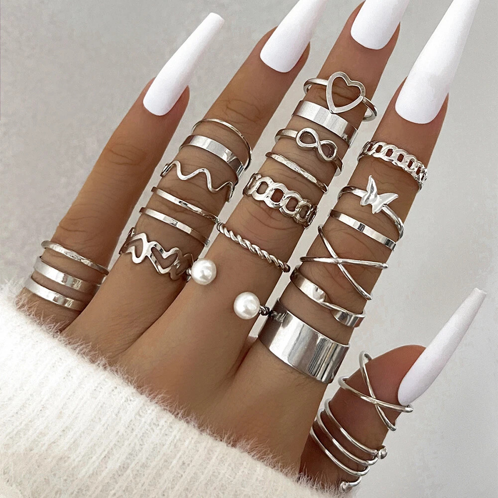 Woman's hand with long white nails and stacked silver rings