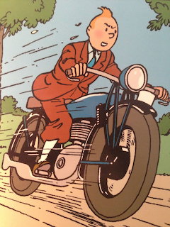Tintin character riding a black motorcycle on a road with trees in the background, comic illustration