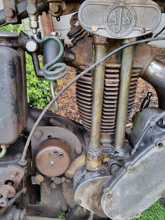 Close-up of vintage AJS Model 26 motorcycle engine showing mechanical components, springs, and weathered metal parts