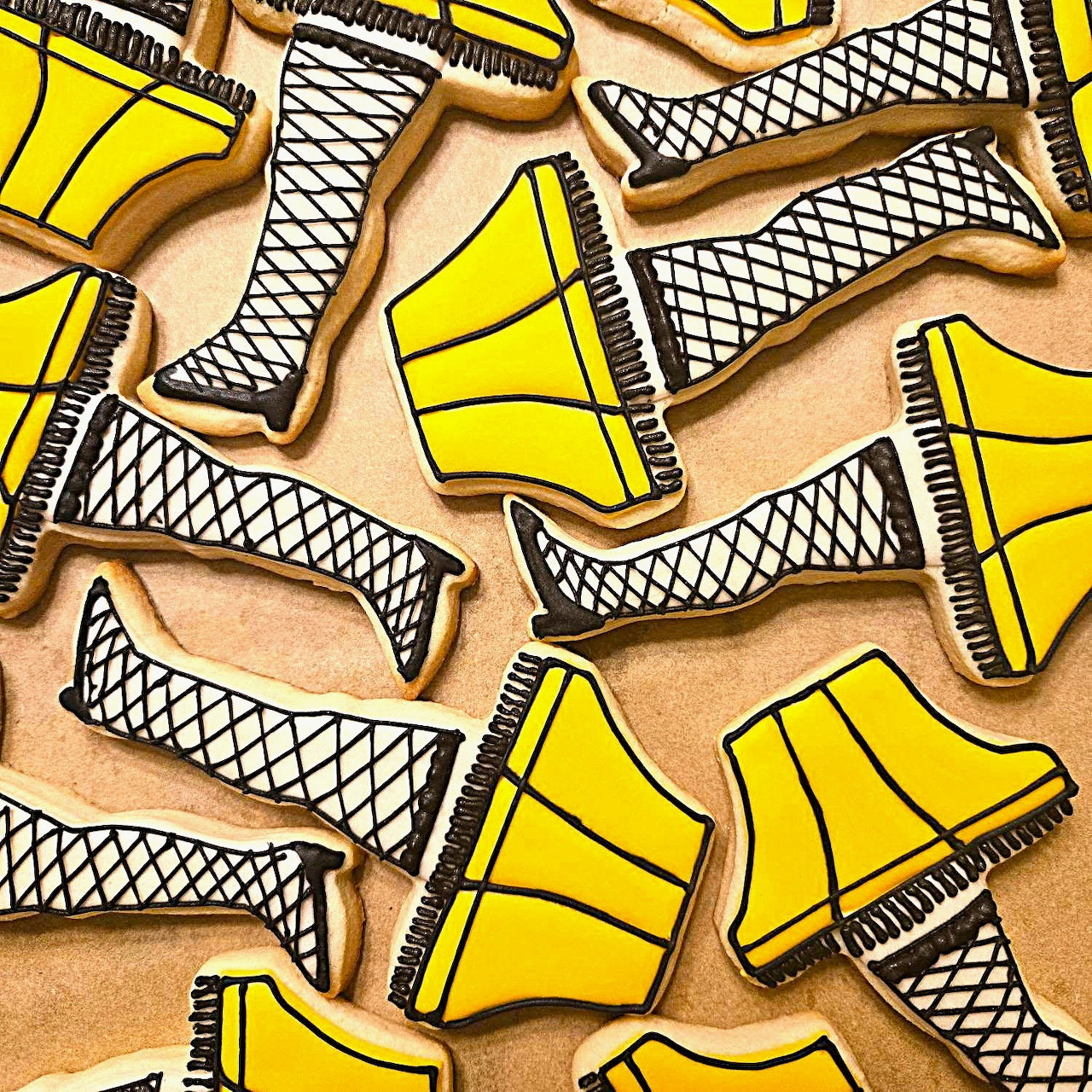 Sugar cookies decorated as leg lamps with fishnet pattern and yellow lampshades on tan background