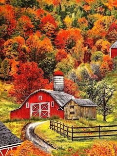 Red barn with silo along a winding road surrounded by colorful autumn trees on a hillside