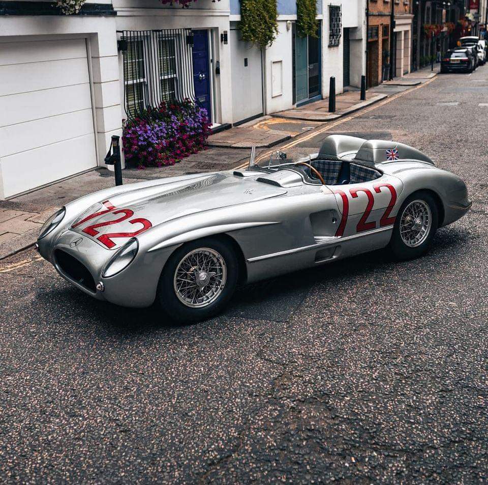 Silver 1955 Mercedes 300 SLR race car numbered 722 on cobblestone street
