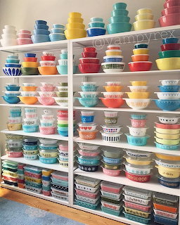 Shelves filled with colorful vintage Pyrex bowls and containers in various patterns and colors