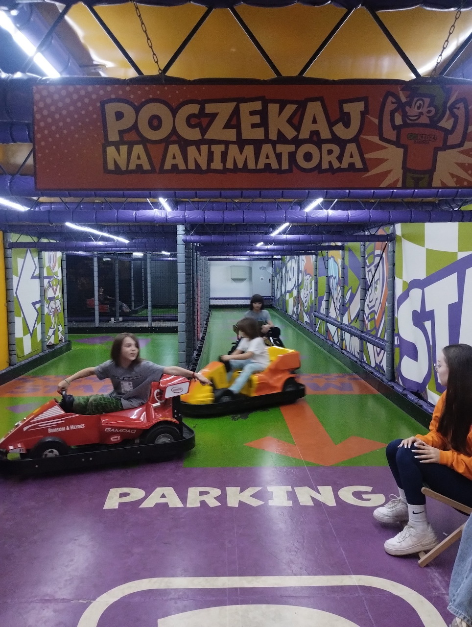 Kids riding red and yellow bumper cars on an indoor track at an amusement center