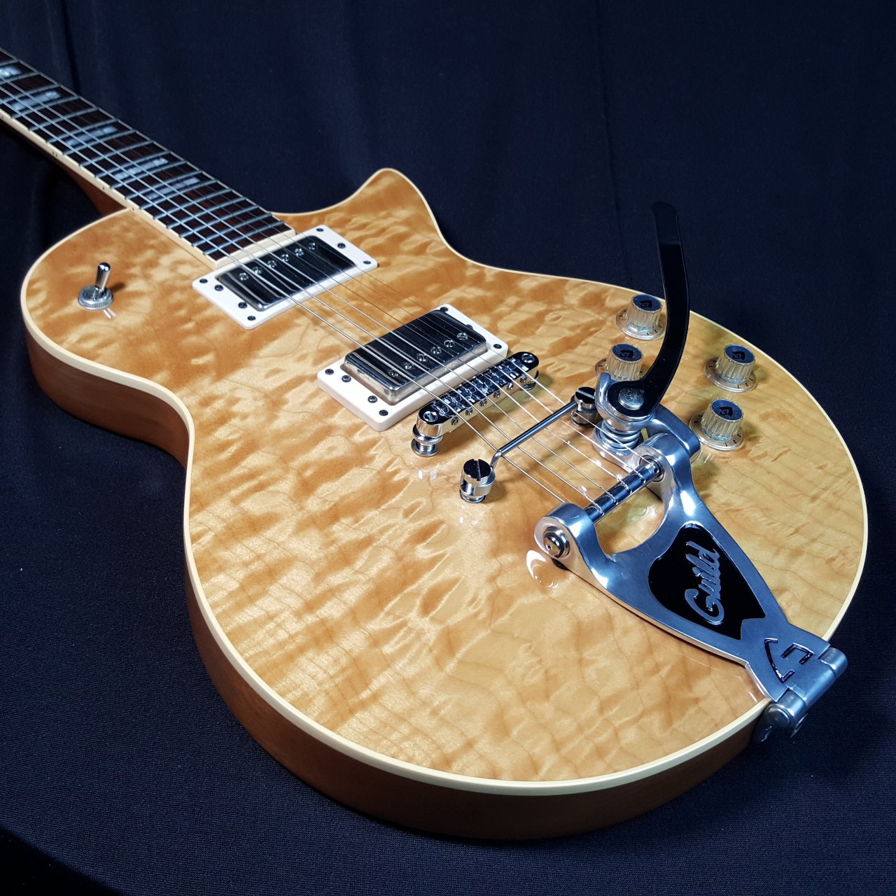 Natural wood electric guitar with chrome hardware on a dark background