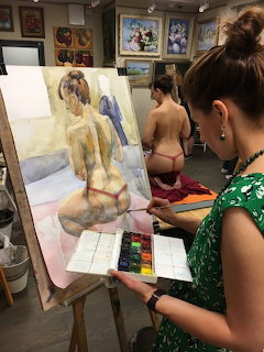 Artist painting nude model on easel in art studio class