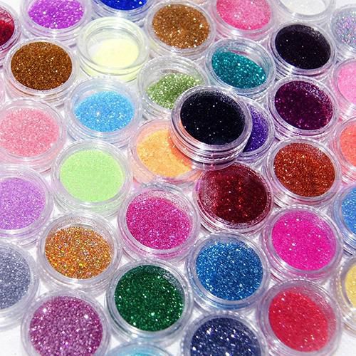 Many small clear containers filled with colorful glitter powder arranged in rows
