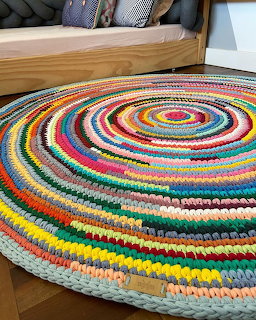 Colorful round crocheted rug with concentric circles of many colors on a light floor