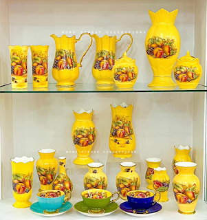 Yellow vintage bone china displayed on glass shelves, including jugs, cups, bowls, and vases