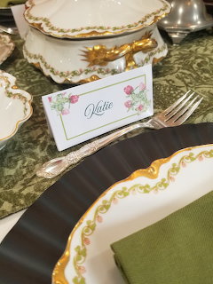 Elegant formal table setting with white porcelain dishes trimmed in gold, silverware, and decorative place card